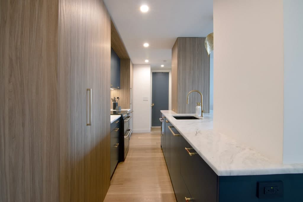 View of the galley kitchen with the pantry cabinets in light wood.