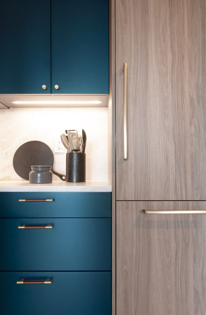 Detail of the MandiCasa cabinets in deep blue and light wood with three different handles in bronze finish.