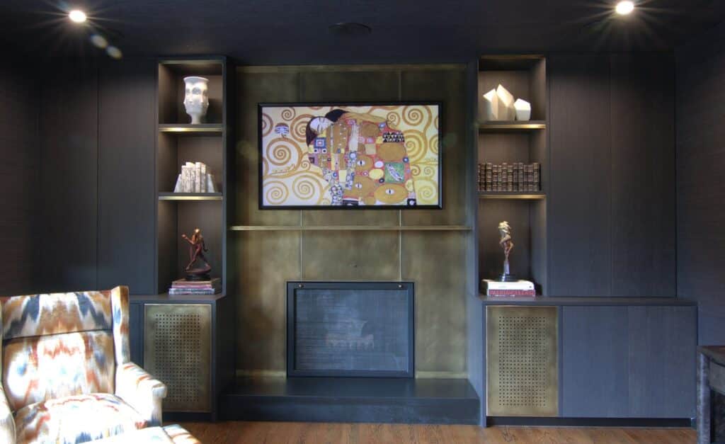 Luxury fireplace framed by Italian dark oak cabinets and bronze panels with fine art and Richard MacDonald sculptures on display