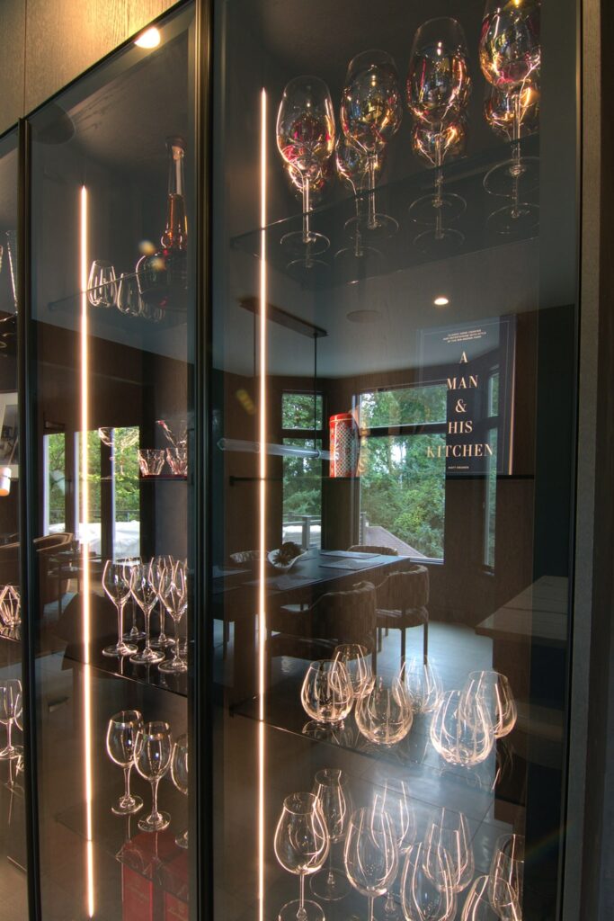 Luxury glass cabinets with black aluminum frame and interior lighting displaying crystals and stemware